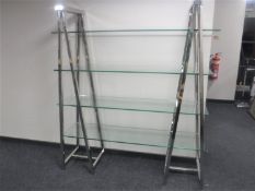 A set of contemporary four tier glass shelves on metal supports
