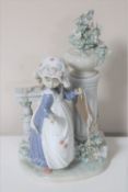 A Lladro figure of a girl with a flower beside a column