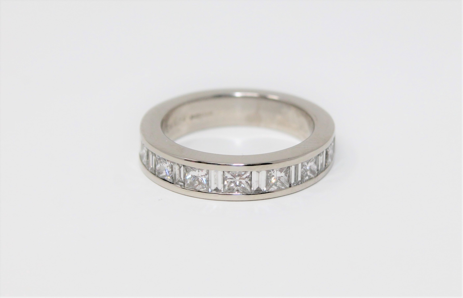 A fine quality platinum and diamond half-eternity ring set with princess and baguette-cut stones,