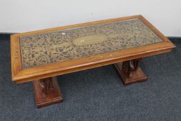 An eastern carved mahogany and brass inlaid coffee table with glass inset panel on elephant