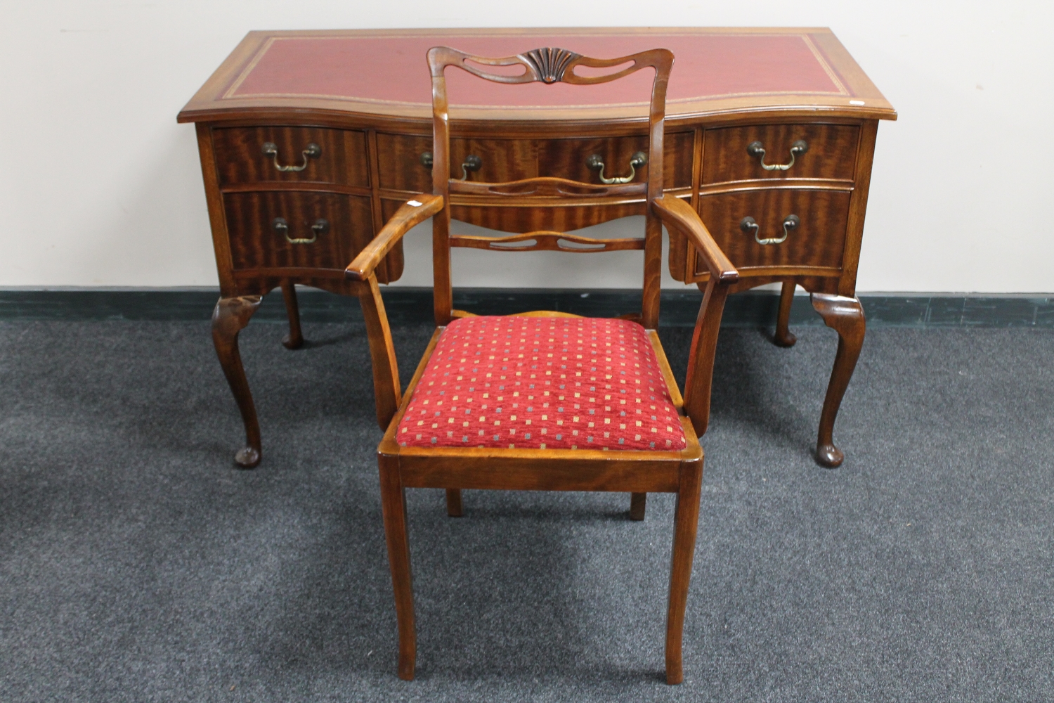 A mahogany serpentine fronted five drawer writing desk with red leather inset panel on Queen Anne