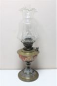 An antique brass Veritas oil lamp with glass chimney and shade