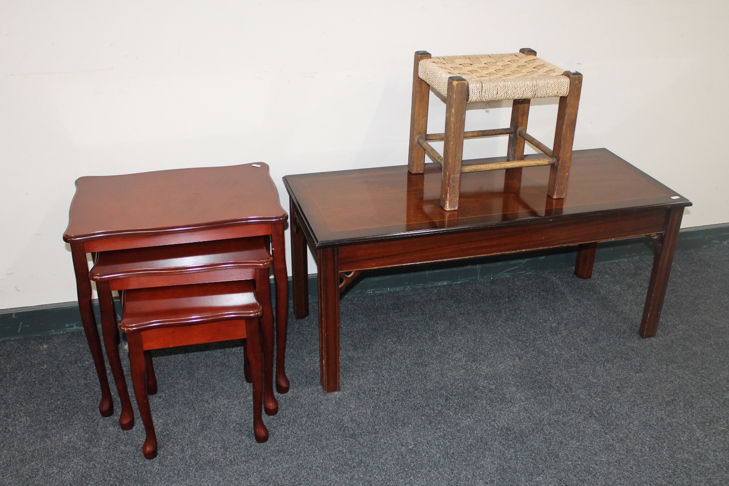 An inlaid mahogany coffee table together with a nest of three tables and a rush seated stool