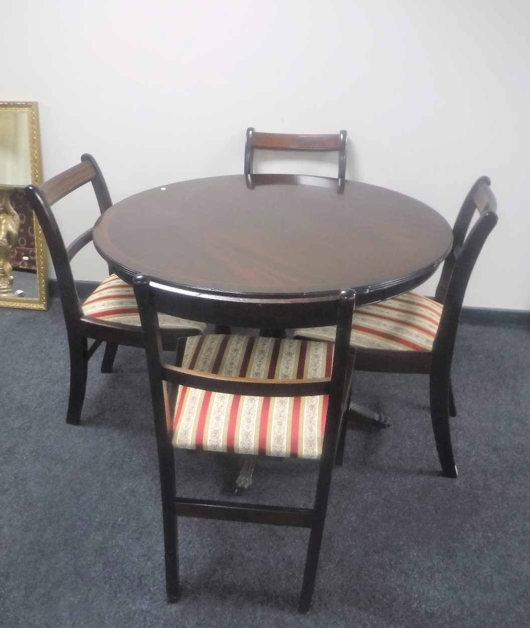 A circular inlaid mahogany Regency style pedestal dining table with four chairs