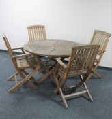 A teak garden table and four folding armchairs
