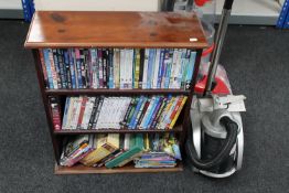 A set of pine bookshelves containing a quantity of assorted DVD's together with a cylinder vacuum