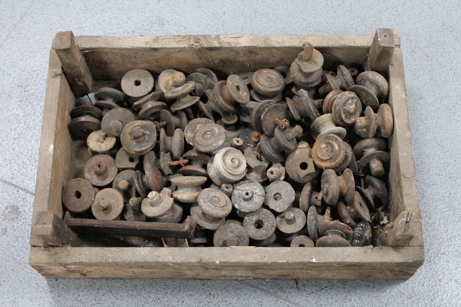 A wooden crate containing a large quantity of antique wooden chest handles