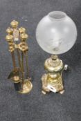 A four-piece brass companion set on stand together with an ornate brass table lamp with glass shade