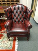An oxblood buttoned leather Chesterfield style wingback armchair, width 95 cm.