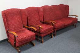 A three piece wood framed wingback lounge suite upholstered in a red fabric comprising of three