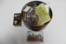 A tin containing a matchbook collection, teaspoons, tin containing foreign coins,
