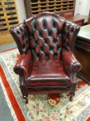 An oxblood buttoned leather Chesterfield style wingback armchair, width 95 cm.