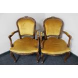 A pair of carved continental salon armchairs upholstered in a gold fabric