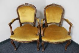 A pair of carved continental salon armchairs upholstered in a gold fabric