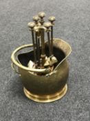 An antique brass coal bucket and four piece companion set on stand