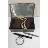 A metal tin containing cloth cutlery bag, silver mechanical pencil, fountain pen,