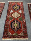 A Caucasian fringed runner on red ground,
