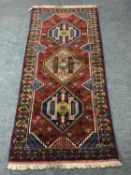 A Caucasian fringed rug on red ground,