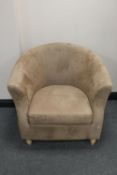 A tub chair upholstered in beige fabric