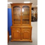 An oak glazed door kitchen dresser fitted with cupboards and drawers beneath