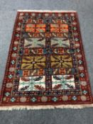 A Caucasian fringed rug on red ground,