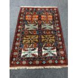 A Caucasian fringed rug on red ground,