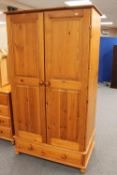 A pine double door wardrobe fitted with a drawer