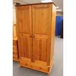 A pine double door wardrobe fitted with a drawer