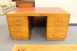 An early twentieth century oak twin pedestal desk fitted with eight drawers