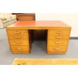 An early twentieth century oak twin pedestal desk fitted with eight drawers