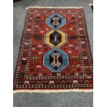 A Caucasian fringed rug on red ground,