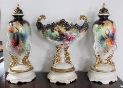 A three piece Victorian pottery vase garniture with bird decoration on stands