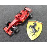 A cast iron Ferrari plaque and a plastic model of a Formula 1 car