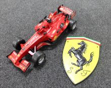 A cast iron Ferrari plaque and a plastic model of a Formula 1 car