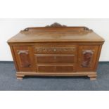 A 20th century carved oak sideboard with walnut panelled doors