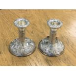 A pair of embossed, filled silver candlesticks,