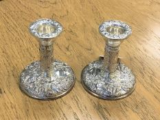 A pair of embossed, filled silver candlesticks,