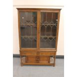 An oak double door bookcase on stand fitted with two drawers