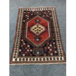 A Caucasian fringed rug on red ground, with floral border,