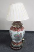 A Chinese floral pottery table lamp with shade on wooden base