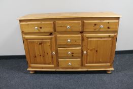 A pine sideboard fitted cupboards and drawers beneath