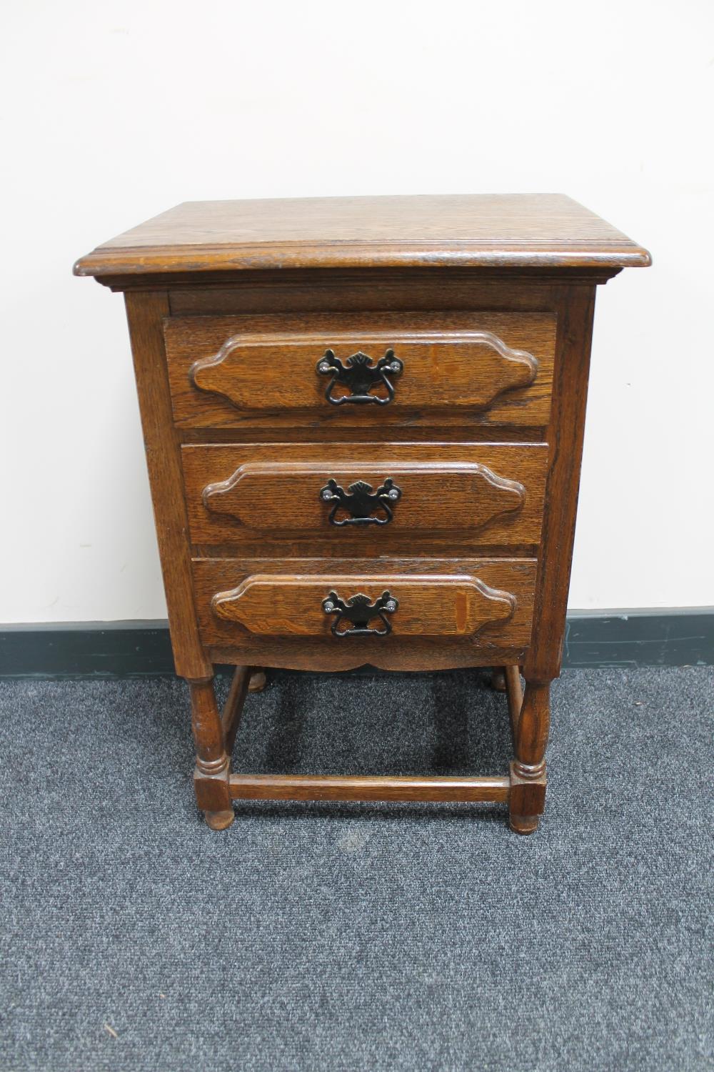 An oak three drawer bedside chest