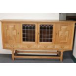 A blonde oak four door sideboard with stained leaded glass panels