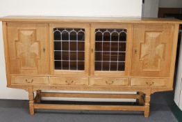 A blonde oak four door sideboard with stained leaded glass panels