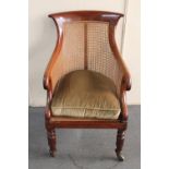 A 19th century mahogany and bergere scroll arm armchair raised on brass castors