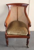 A 19th century mahogany and bergere scroll arm armchair raised on brass castors