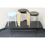 A contemporary black ash coffee table on chrome legs together with two pairs of stools