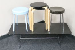 A contemporary black ash coffee table on chrome legs together with two pairs of stools
