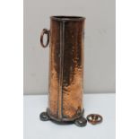 An antique hammered copper vase on metal feet