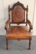 A 19th century heavily carved oak armchair in tooled leather (finial missing)